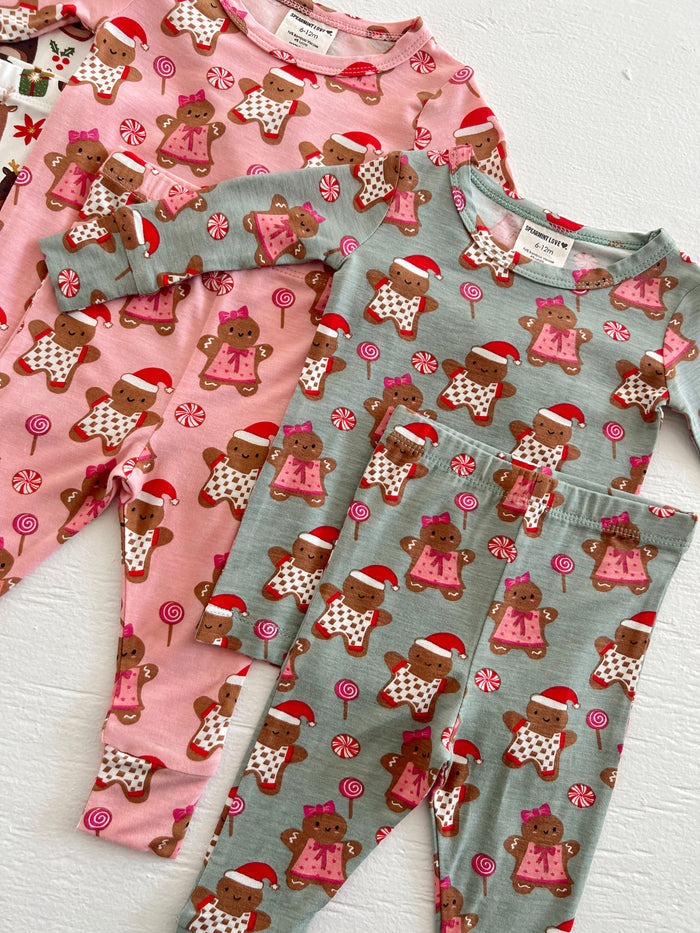 Colorful children’s pajamas featuring gingerbread men in Santa hats and candy motifs on a white background.