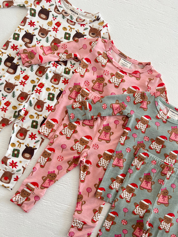 Four pairs of festive children's pajamas featuring reindeer and gingerbread designs in playful colors.