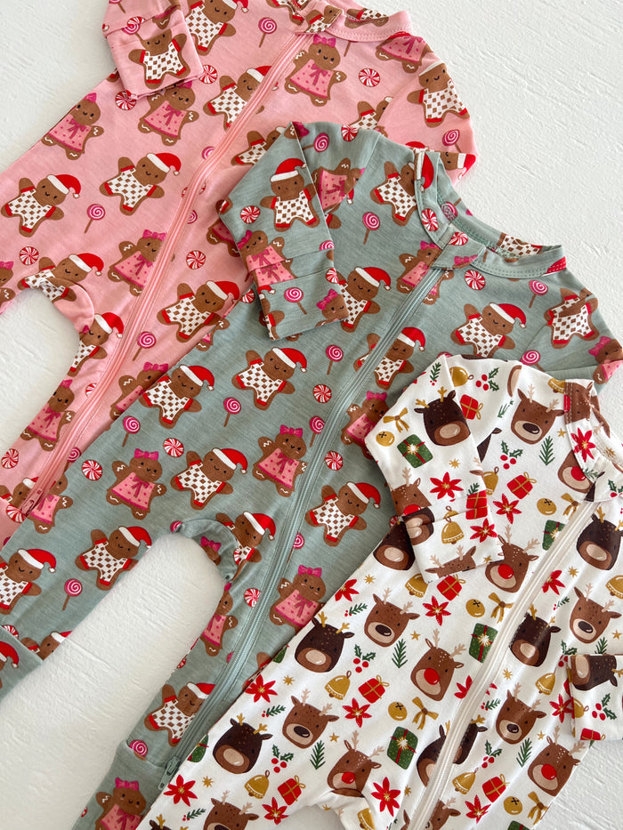 Three festive infant onesies featuring gingerbread and reindeer patterns in pink, green, and white colors.