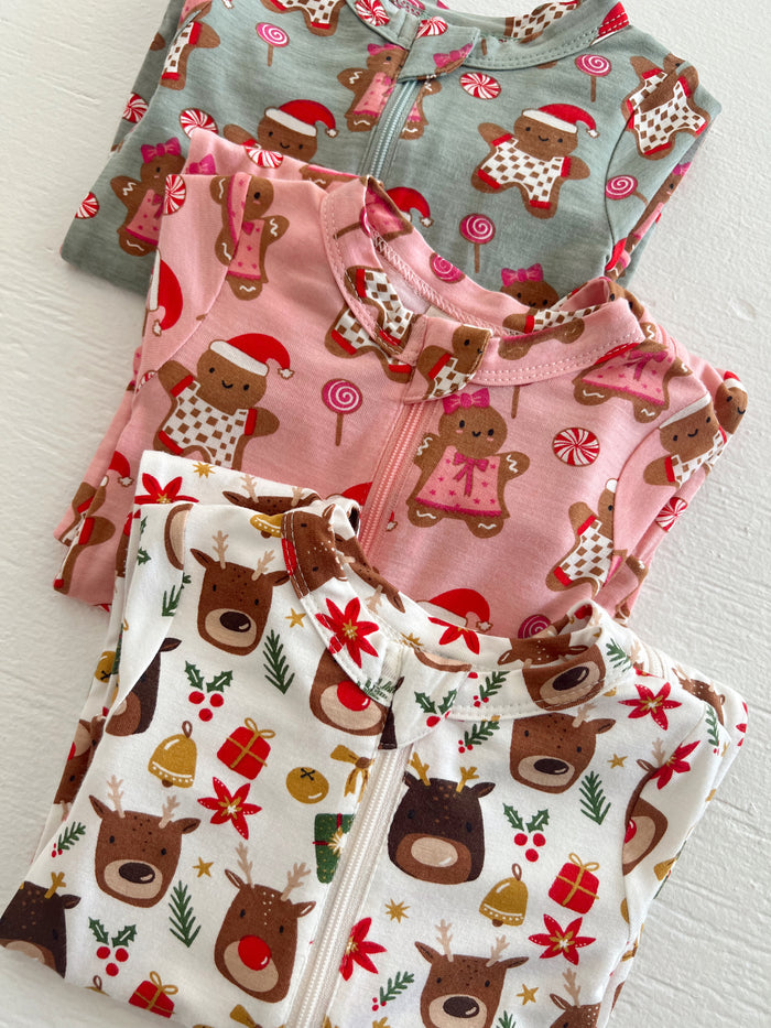 Three festive children's pajamas featuring gingerbread and reindeer patterns in holiday colors.