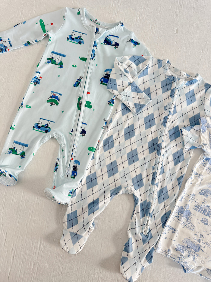 Two baby onesies in blue designs: one with golf carts, the other in a blue argyle pattern on a white background.
