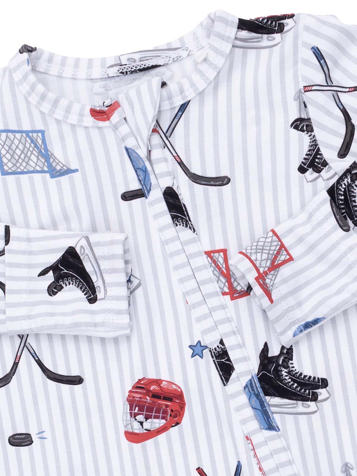 Kid's pajama top featuring hockey-themed graphics like skates, pucks, and nets on a striped background.