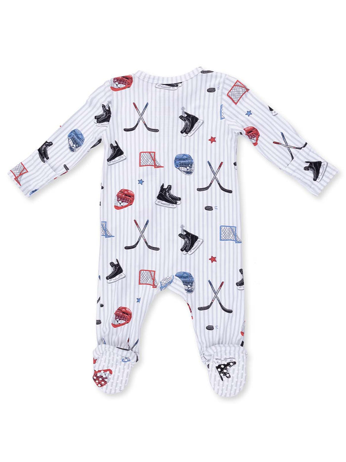 Baby pajama suit with hockey-themed prints including skates, helmets, and sticks on a striped background.