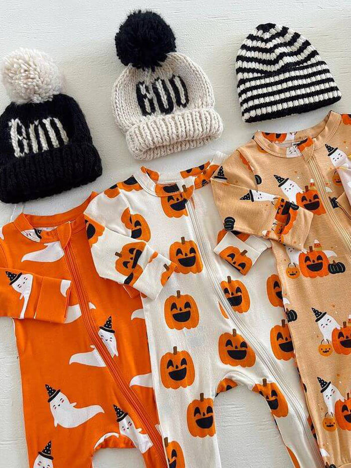 Three festive baby onesies with pumpkin and ghost designs, paired with knitted hats in black and white.