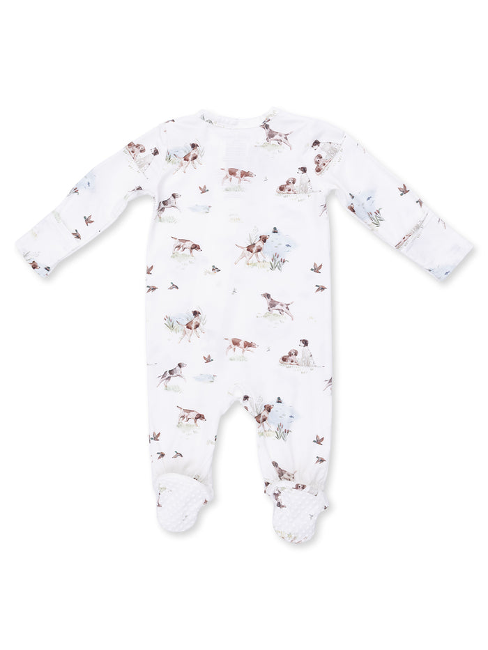 White baby onesie with playful dog and nature print, featuring long sleeves and footed design.
