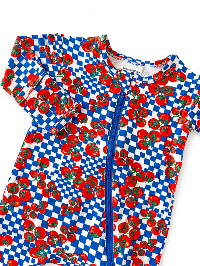 Colorful toddler swim onesie with red tomatoes and blue checkered pattern, featuring a front zipper.