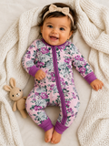 Smiling baby in floral pajamas with a bow headband, cuddling a plush bunny on a cozy blanket.