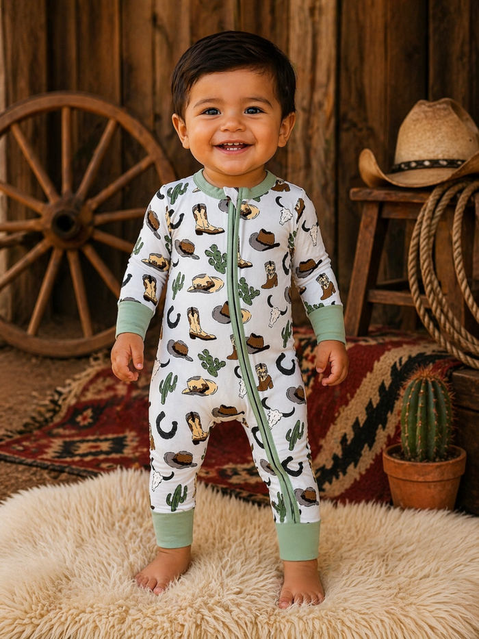 Smiling toddler in a playful, patterned onesie standing on a fluffy rug with rustic decor in the background.