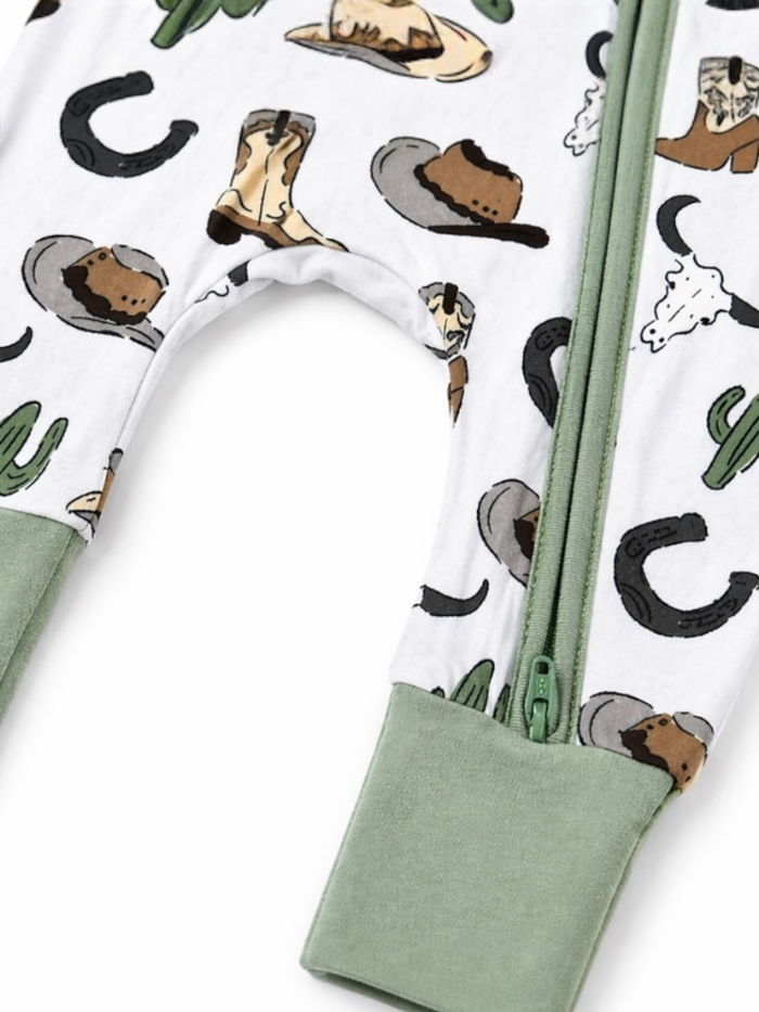 Children's romper featuring hats, cowboy boots, and cacti in a playful design with a green zippered closure.