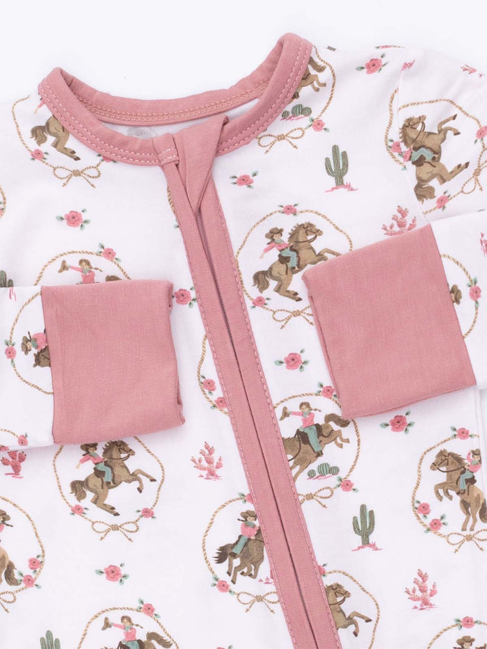 Child's zip-up outfit featuring a playful cowboy and horse print with pink accents and floral designs.