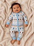 Smiling baby in a sporty onesie on a cozy blanket, surrounded by playful football-themed patterns.