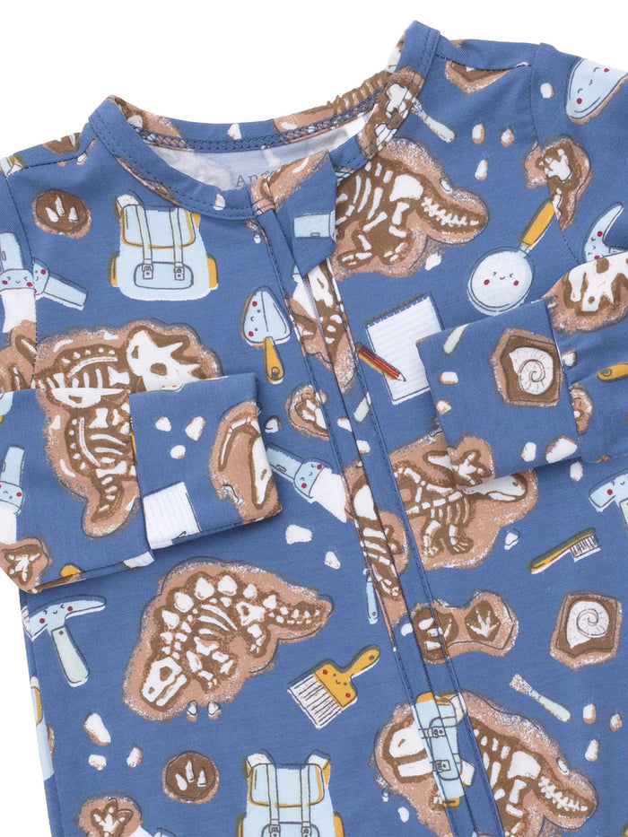 Blue children's pajamas featuring a playful dinosaur skeleton and art supplies pattern.