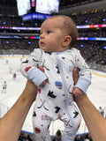 Baby in hockey-themed onesie held above a crowd at an ice hockey game, focused on their curious expression.