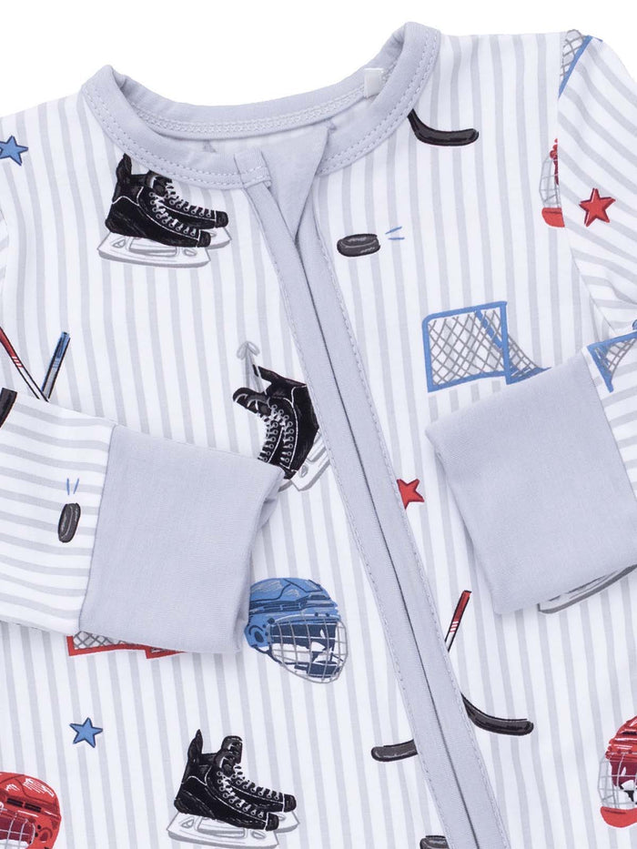Children's pajamas featuring hockey-themed graphics, including skates, pucks, and nets on a striped background.