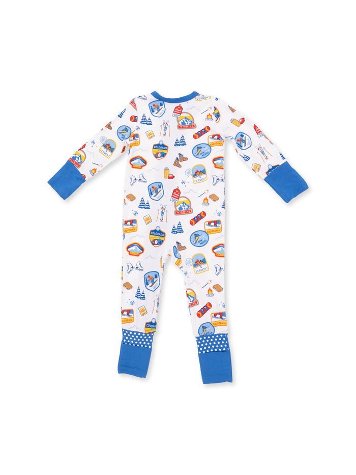 Colorful children's pajamas with ski and outdoor-themed patterns, featuring blue accents and polka dot cuffs.