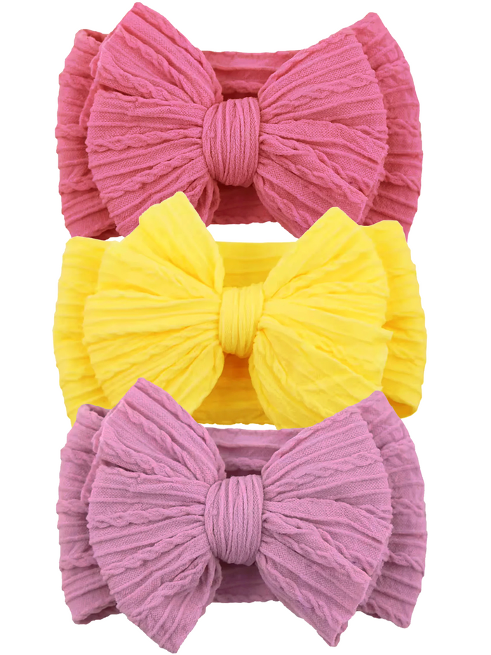 Three textured hair bows in pink, yellow, and lavender stacked vertically on a white background.