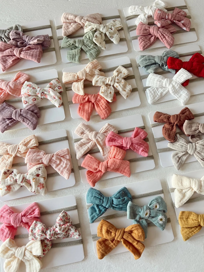 Colorful hair bows displayed on cards, featuring various patterns and textures in pastel shades.