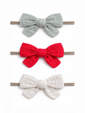 Three fabric hair bows in gray, red, and white on elastic bands, arranged vertically against a white background.