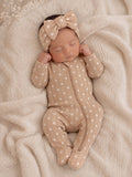 Newborn baby girl sleeping on a cozy blanket, wearing a floral onesie and a matching headband.