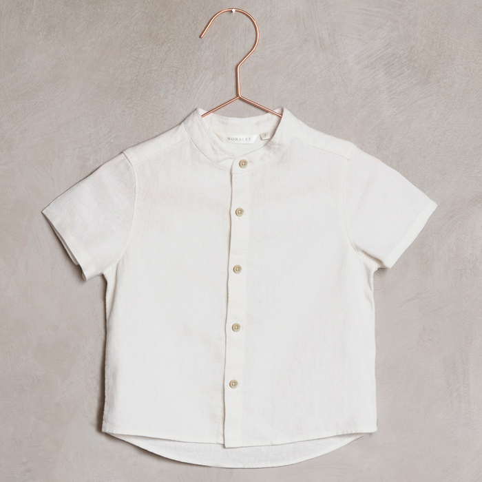 Short-sleeve white button-up shirt hanging on a copper hanger against a textured background.