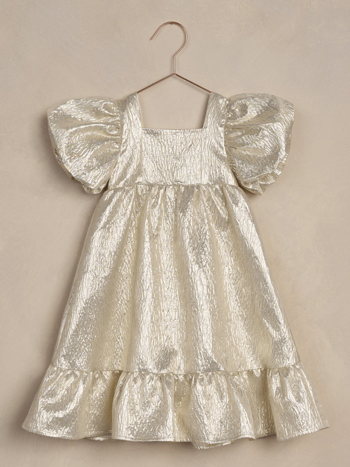 Shiny silver dress with puff sleeves and a ruffled hem, hanging on a hook against a textured background.