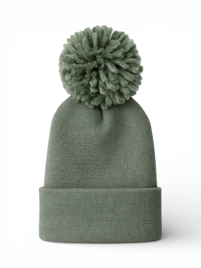 Green knit beanie with a fluffy pom-pom on top, set against a white background.