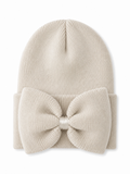 Cream beanie hat with a large bow on the front, perfect for winter fashion.