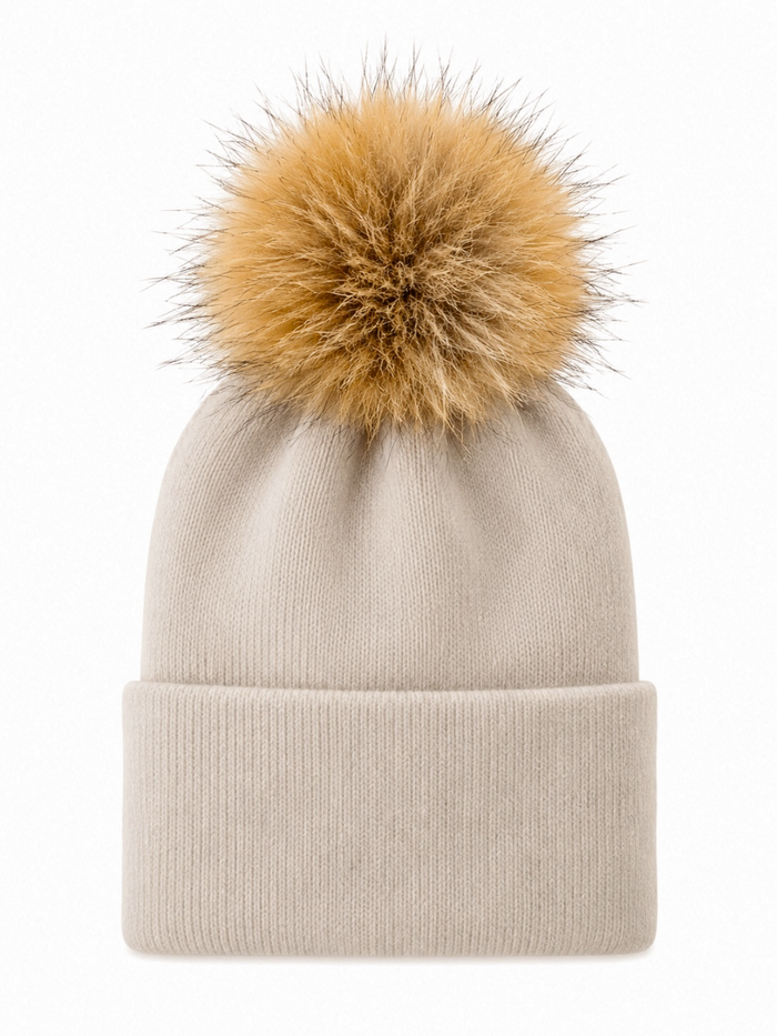 Beige knit beanie with a large fluffy golden pom-pom on top.