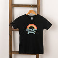 Black t-shirt hanging on a wooden ladder, featuring a colorful rainbow graphic and the text "Better than Great."