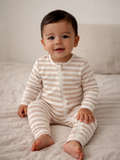 Smiling baby in striped pajama sitting on a soft blanket, showcasing a cozy and cheerful atmosphere.