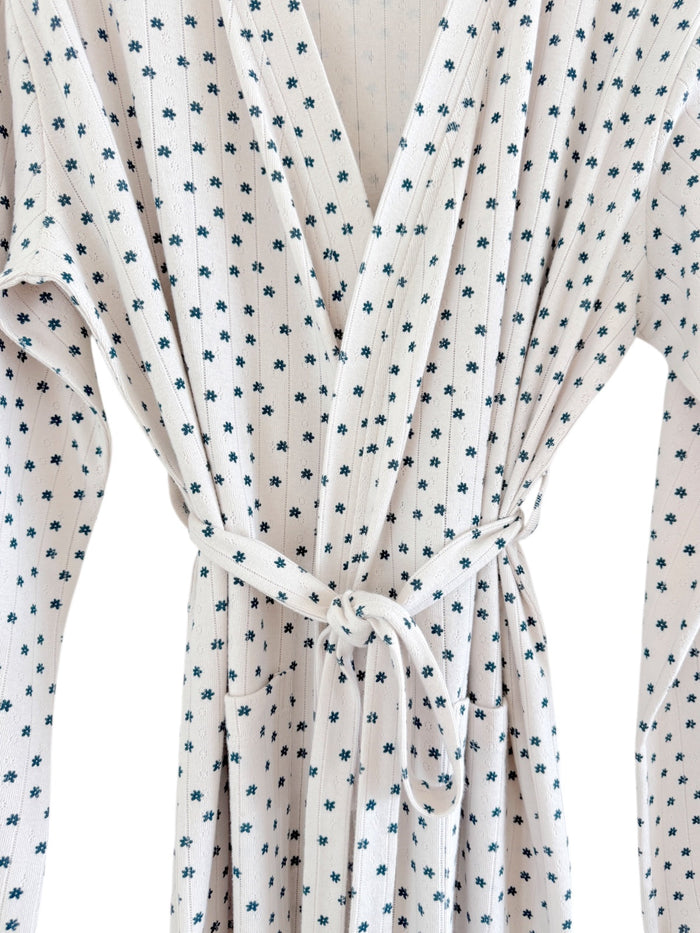 Wrap dress featuring small floral patterns in blue on a white background, tied at the waist with pockets.