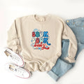 Beige sweatshirt with "Boom Boom Baby" design, paired with light jeans and white sneakers. Ideal for casual wear.