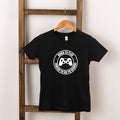 Black t-shirt with white graphic saying "Born to Play, Forced to Go to School" and a gaming controller design.