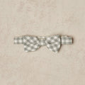 Gray and white checkered bow tie on a beige textured background.