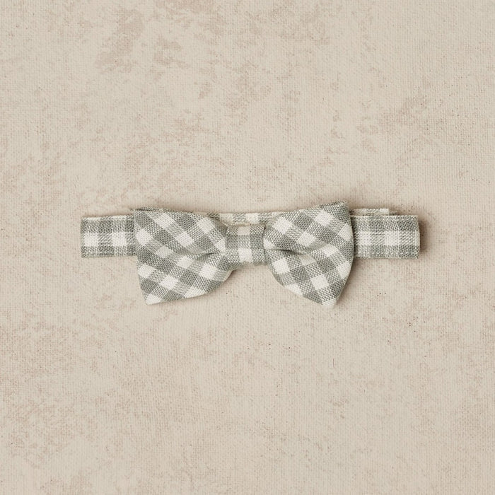 Gray and white checkered bow tie on a beige textured background.