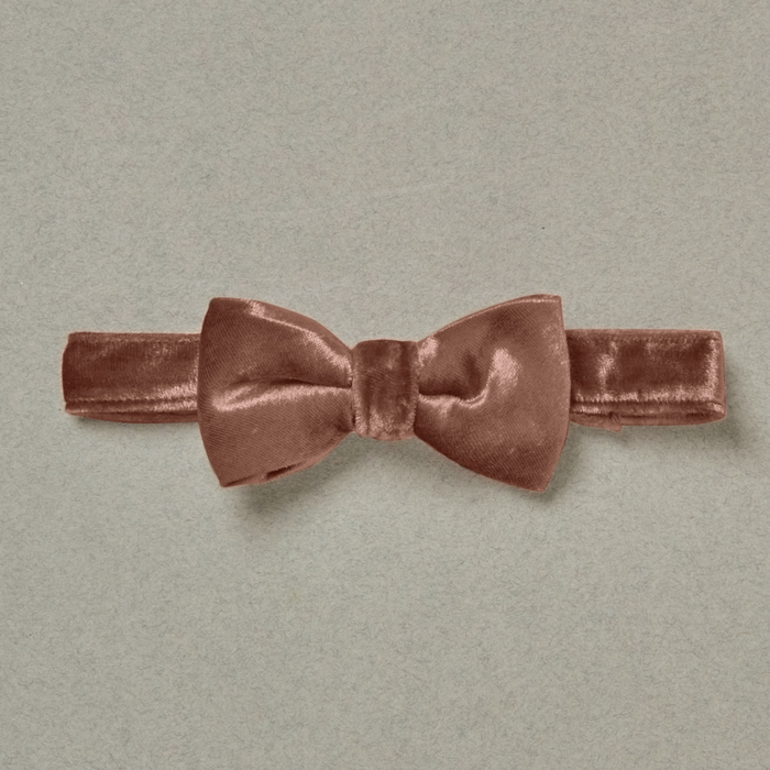 Rose velvet bow tie on a light gray background, showcasing its soft texture and elegant design.