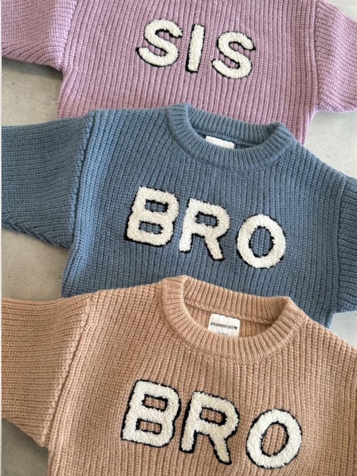Three knit sweaters in pastel colors with the words "SIS" and "BRO" prominently displayed on them.