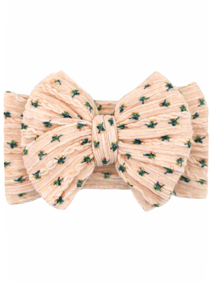 Pink floral hair bow with textured fabric and green accents. Ideal accessory for adding style.
