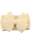 Light yellow hairband with a textured, oversized bow design. Ideal for trendy hairstyles.