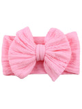 Pink textured headband with a large bow, ideal for children or fashion accessories.