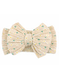 Beige hair bow with green and yellow floral design on a textured fabric. Ideal for stylish hair accessories.