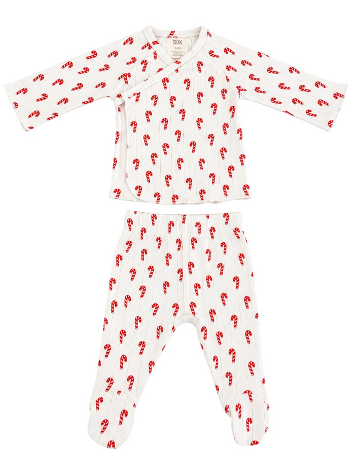 Baby pajama set featuring white fabric with red candy cane print, includes long-sleeve top and footed pants.