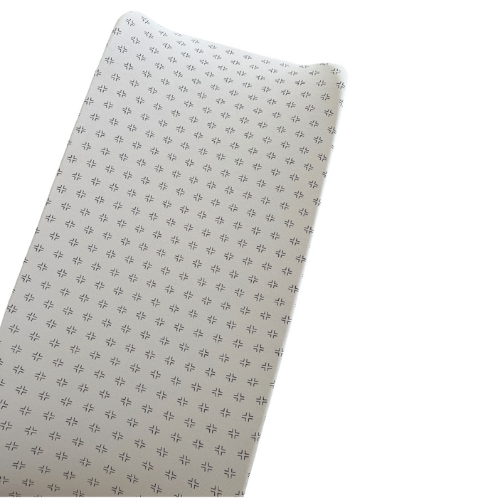 Textured fabric surface with small patterned designs on a light background. Ideal for soft furnishings or upholstery.