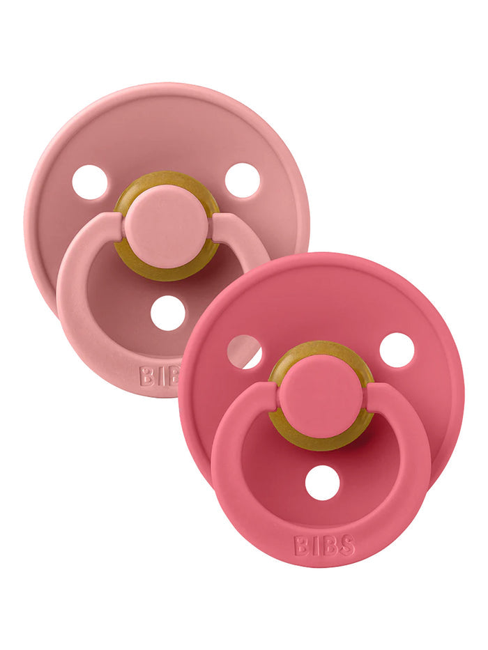 Two pink baby pacifiers on a white background, featuring BPA-free materials and a classic round design.