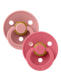 Two pink baby pacifiers on a white background, featuring BPA-free materials and a classic round design.