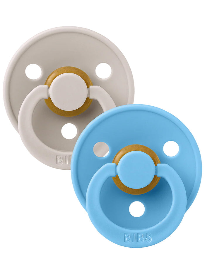 Two pacifiers, one light gray and one blue, each with a gold accent and circular design.