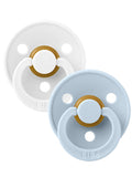 Two pacifiers in white and light blue with a gold accent, featuring a circular design and ventilation holes.