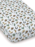 Light blue crib sheet featuring a western pattern of boots, hats, cacti, horseshoes, and cow skulls.