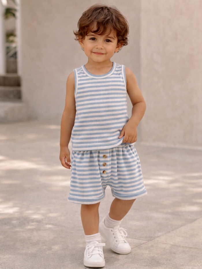 Smiling child in a blue and white striped outfit, standing on a sunny pathway.