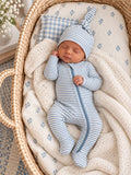 Newborn baby asleep in a cozy bassinet, dressed in blue and white striped sleeper with a matching hat.